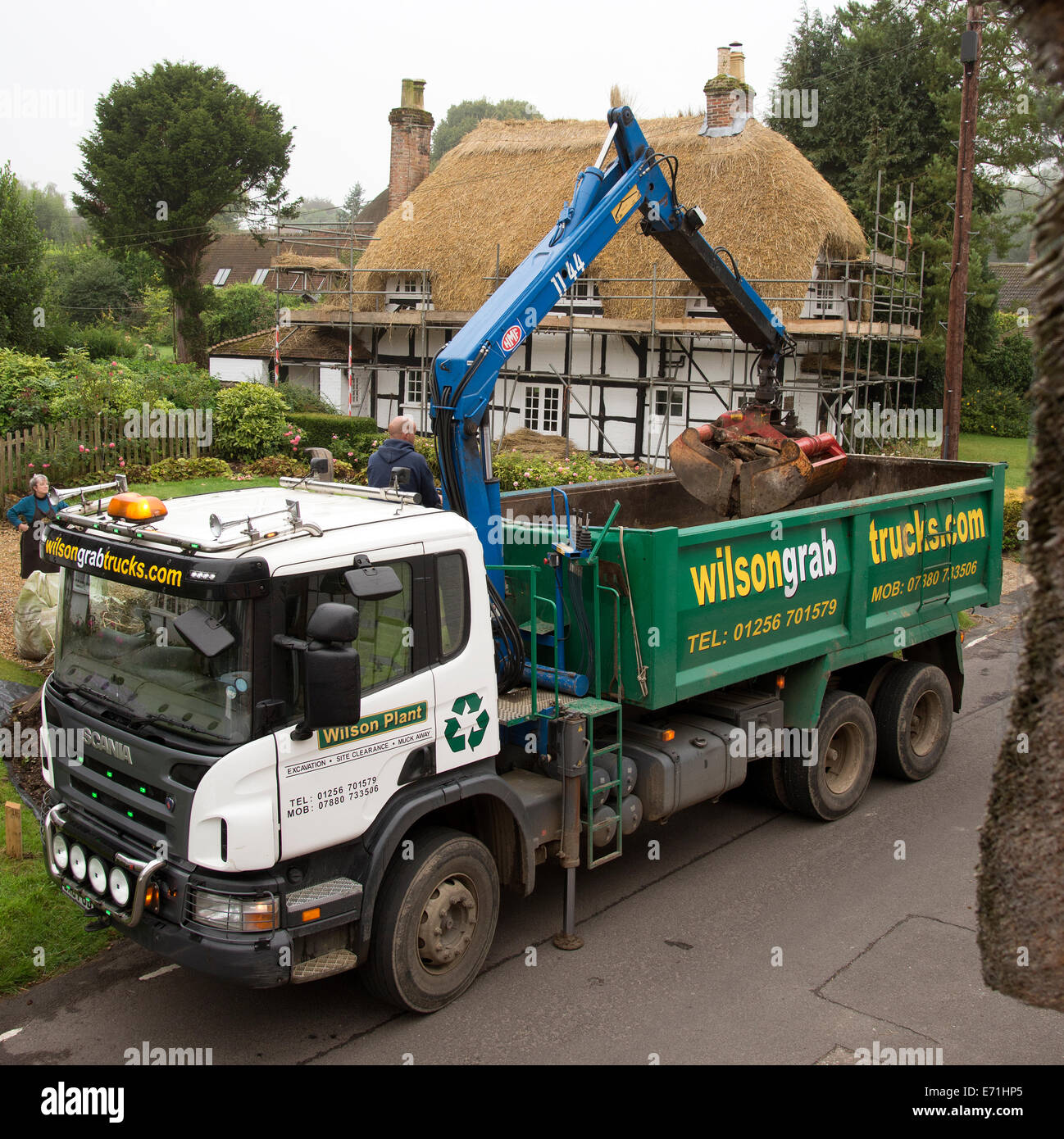A grab truck with crane in action loading bricks and paving. Waste