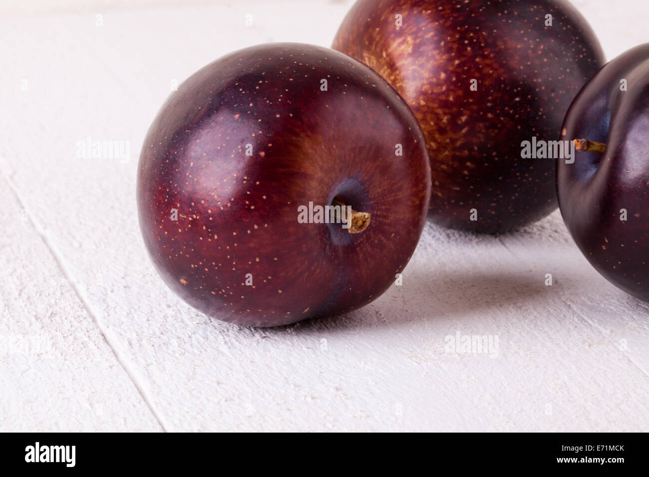 Fresh ripe red juicy appetizing plum close up view with the stalk facing the camera in a concept of healthy eating and diet with Stock Photo