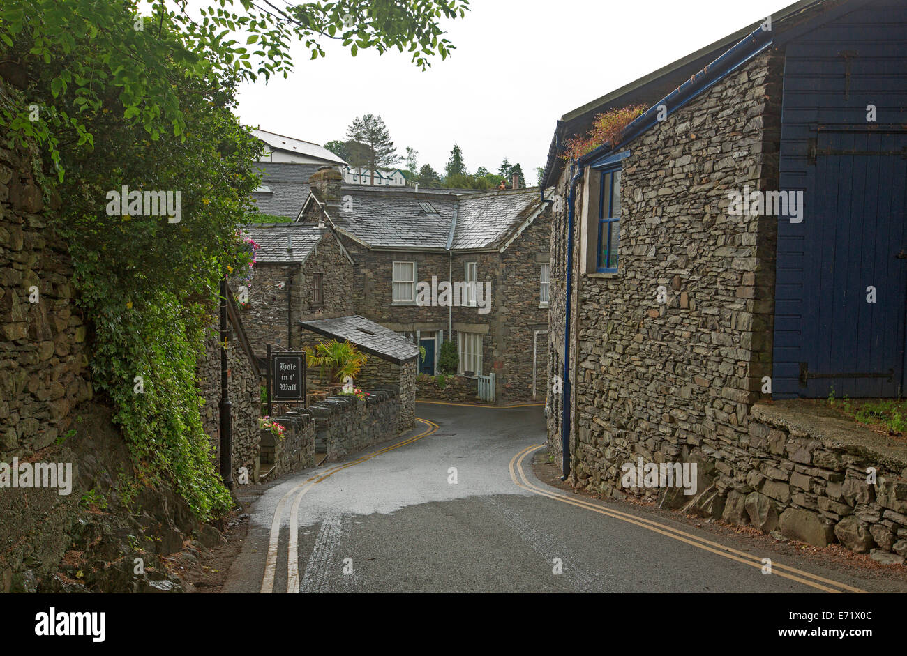 Narrow road winding between historic stone buildings in old English village near Windemere, Lake District, Cumbria, England Stock Photo