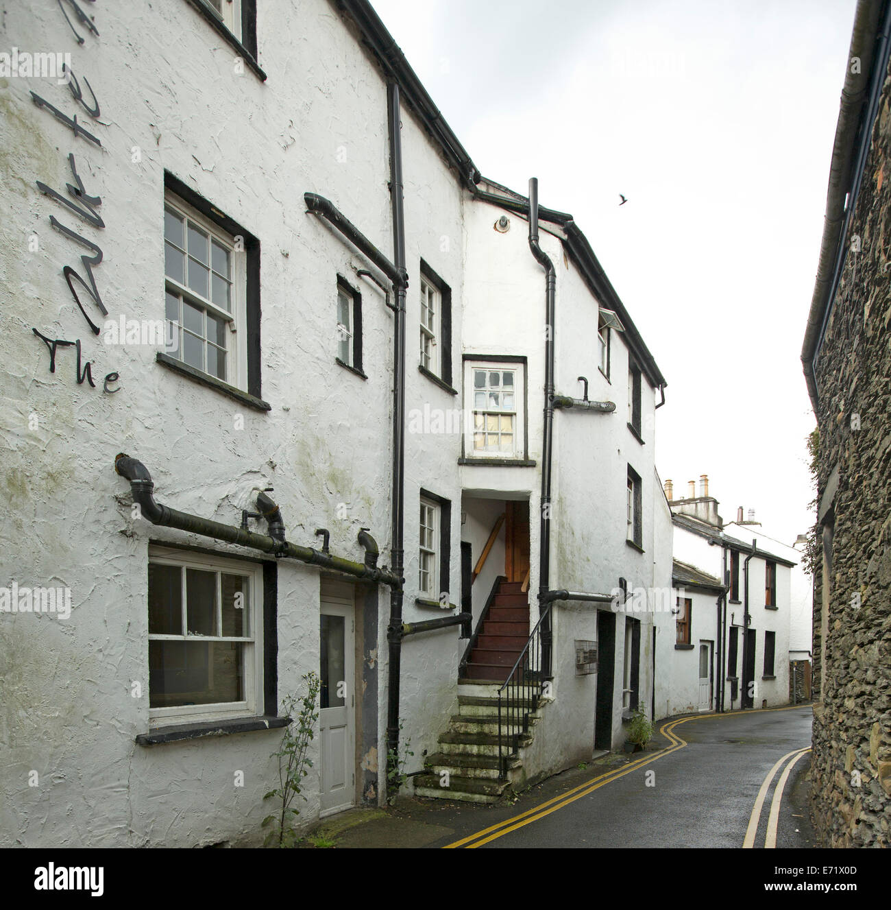 Narrow road winding through white painted stone buildings in old English village near Windemere, Lake District, Cumbria, England Stock Photo
