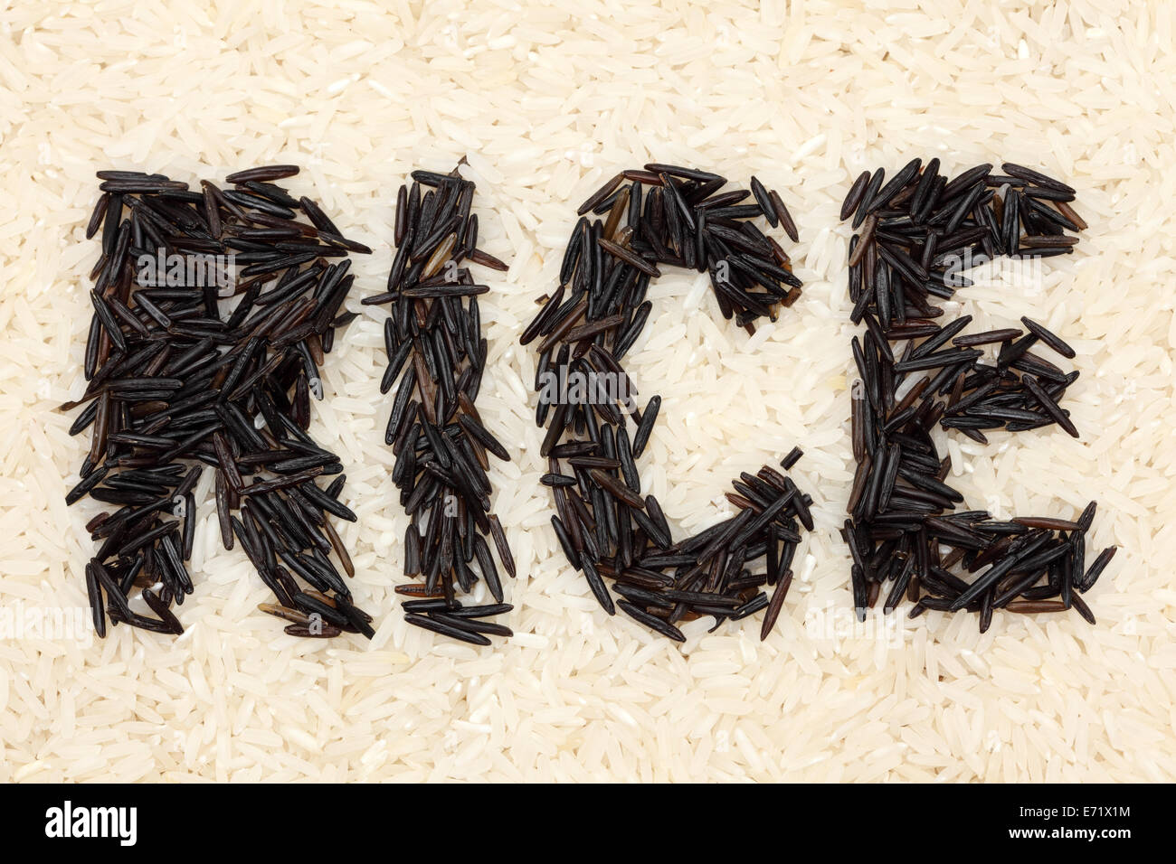 Word "RICE" written with wild rice on a white rice background. Closeup. Stock Photo