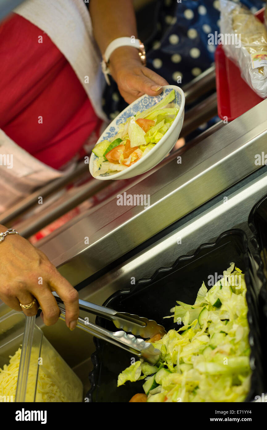 Secondary education Wales UK - a woman serving healthy option food salad for lunch in the school canteen cafeteria Stock Photo