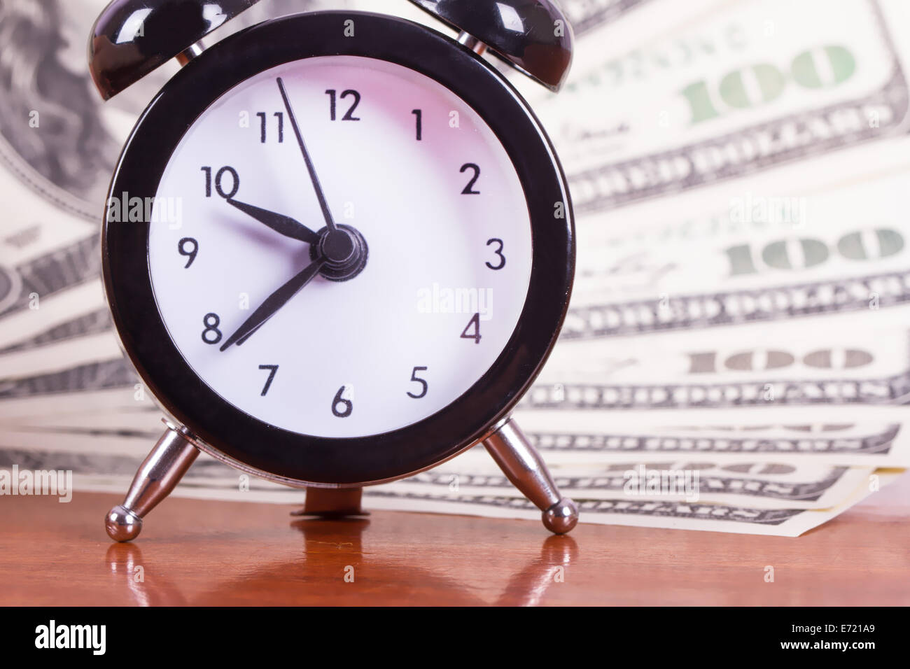 Finance concept, alarm clock and one hundred dollar banknotes on wooden