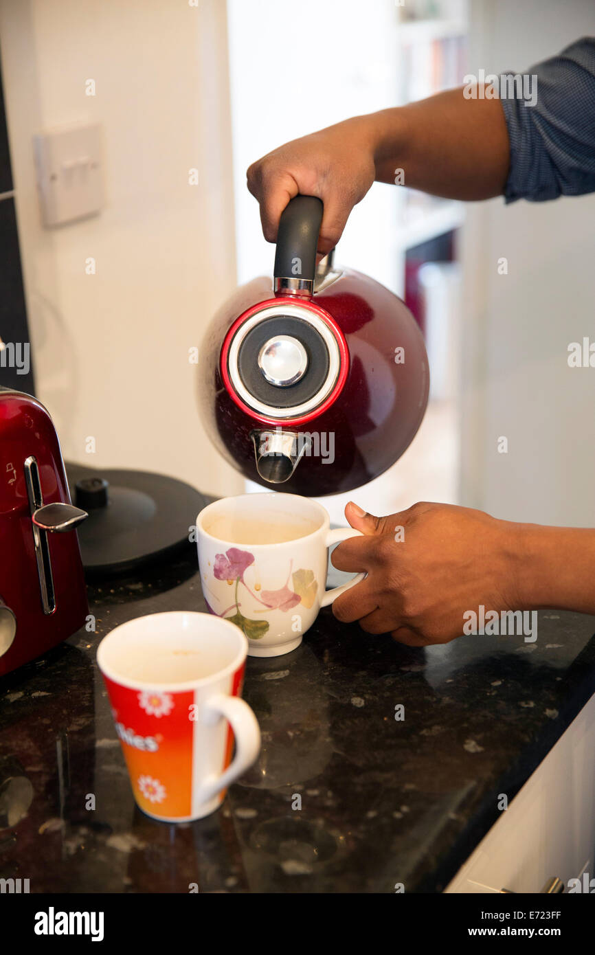 young black man making tea in kitchen Stock Photo
