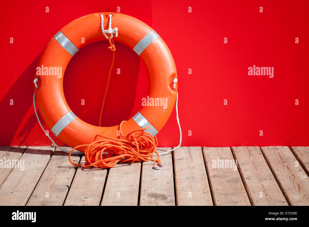Lifebuoy stands on wooden floor nearby red wall of lifeguard station Stock Photo