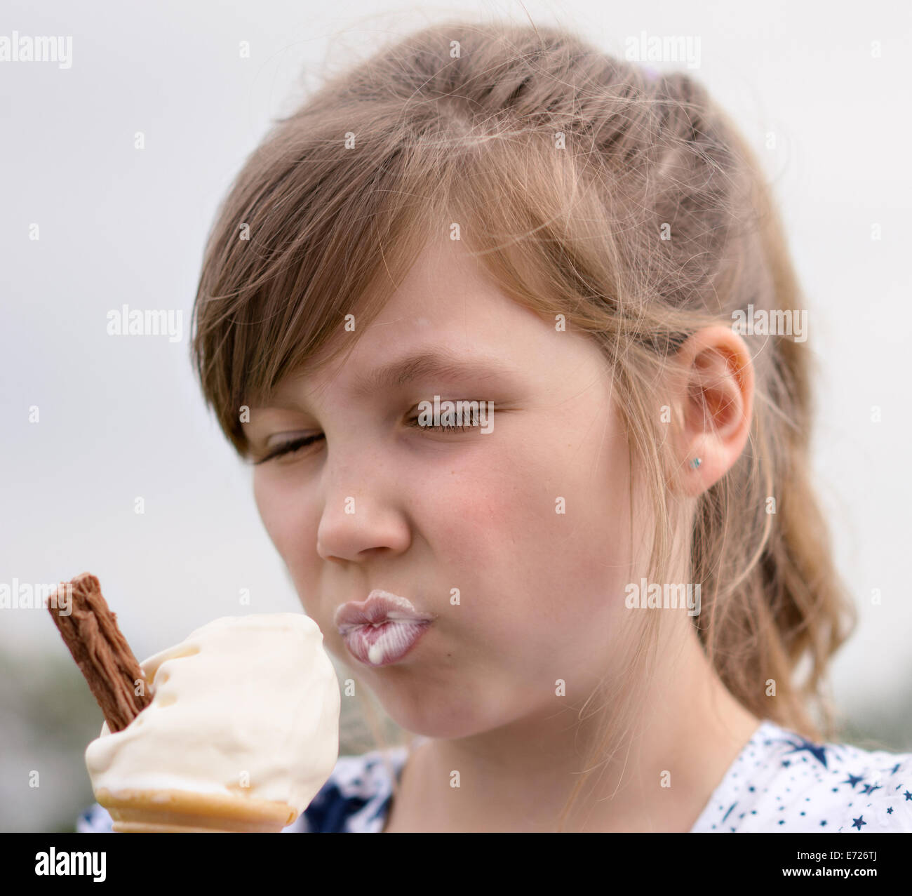 Pretty young girl eating ice cream in the summer sun by the seaside Stock Photo