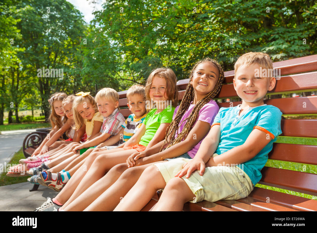 Happy children sit on the bench in park Stock Photo - Alamy