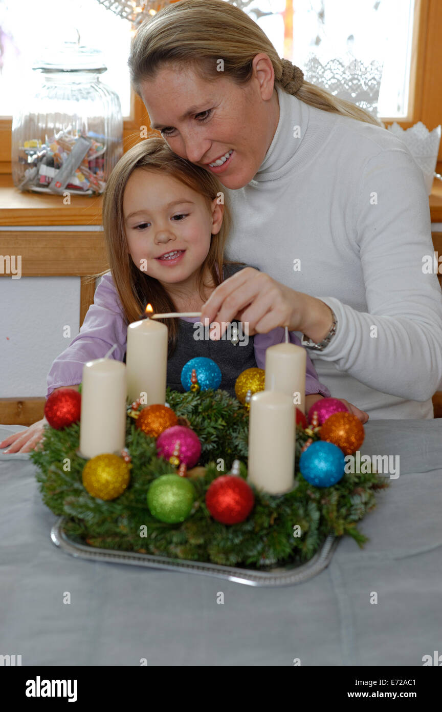 Mother and daughter lighting the first candle on the Advent wreath, first Sunday in Advent Stock Photo