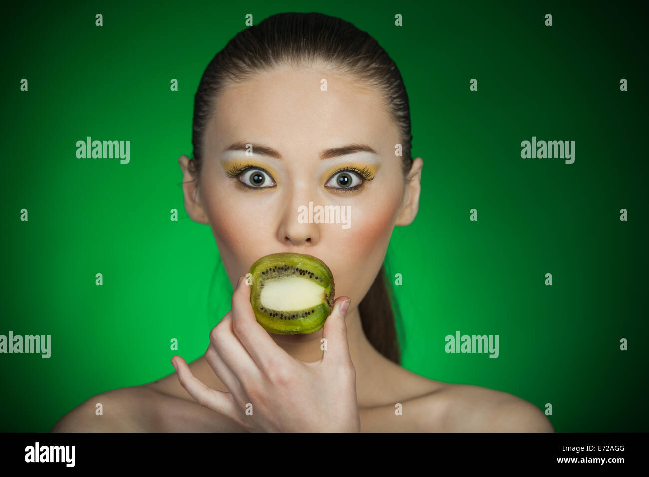Beauty portrait of a girl with kiwi on a green background Stock Photo ...