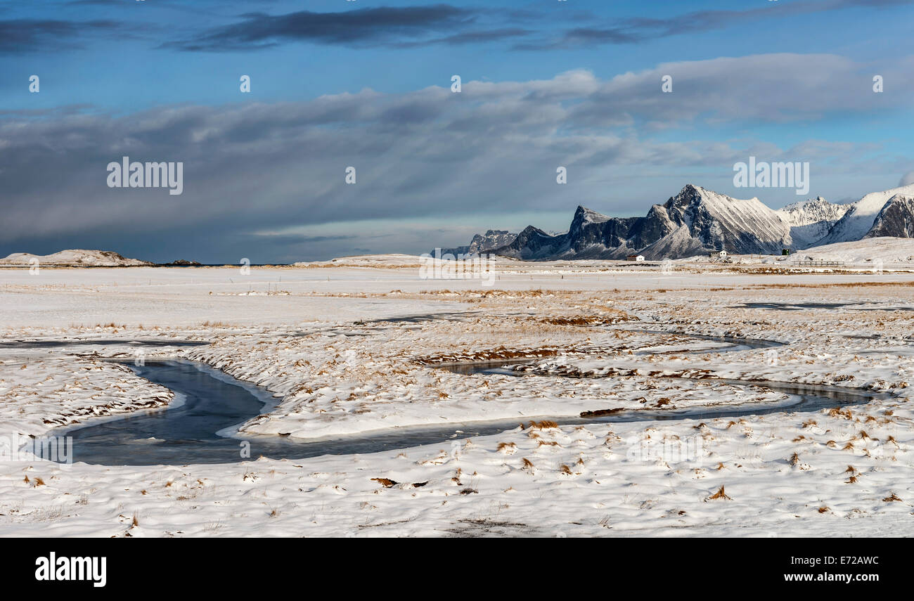 A frozen stream meandering through the snow at Fredvang on the Lofoten islands Stock Photo