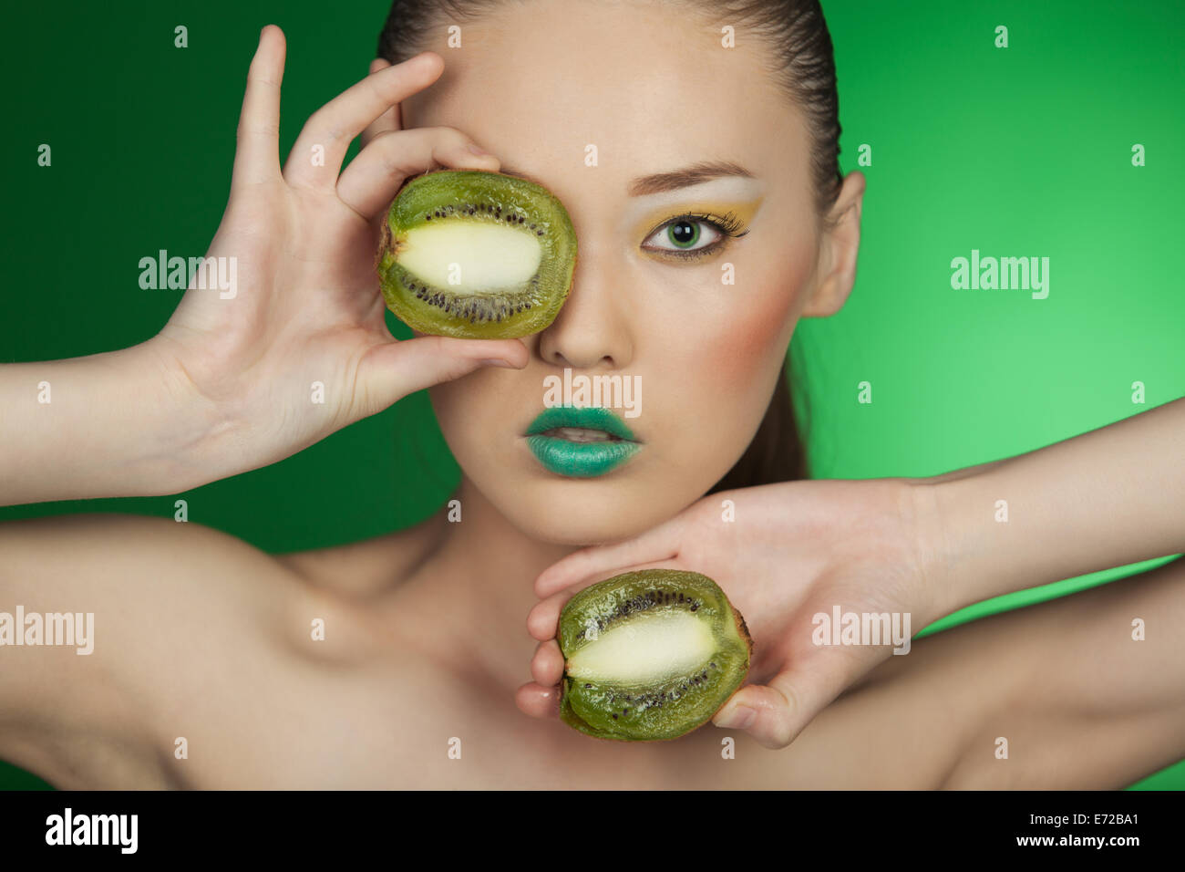 Beauty portrait of a girl with kiwi on a green background Stock Photo ...
