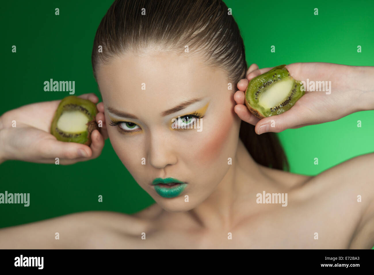 Beauty portrait of a girl with kiwi on a green background Stock Photo ...