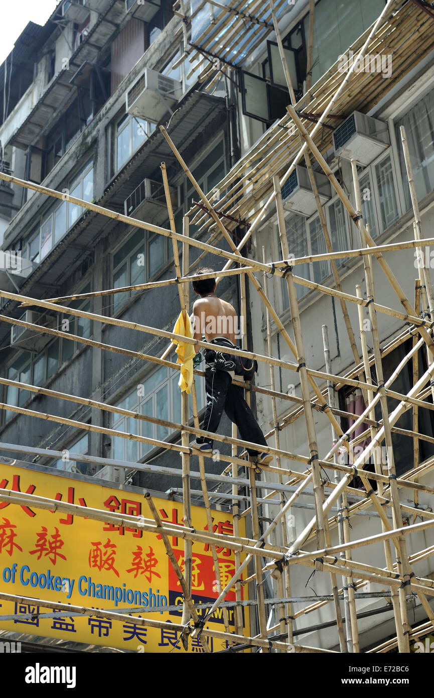 Man standing in scaffolding made from bamboo poles. Kowloon, Hong Kong, China Stock Photo
