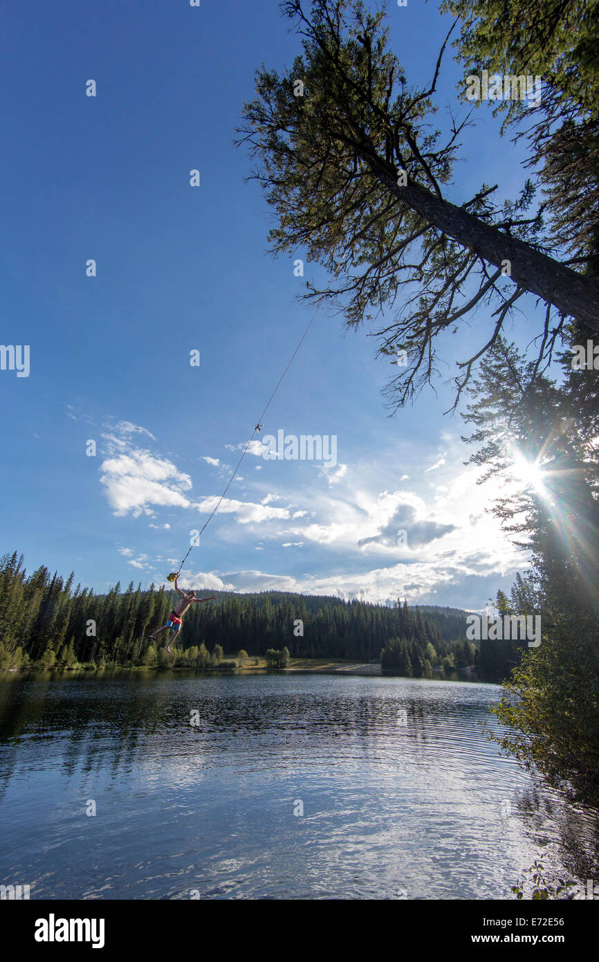 Jumping off a tree rope on a summer day at Champion Lakes Provincial Park, British Columbia, Canada (MR). Stock Photo