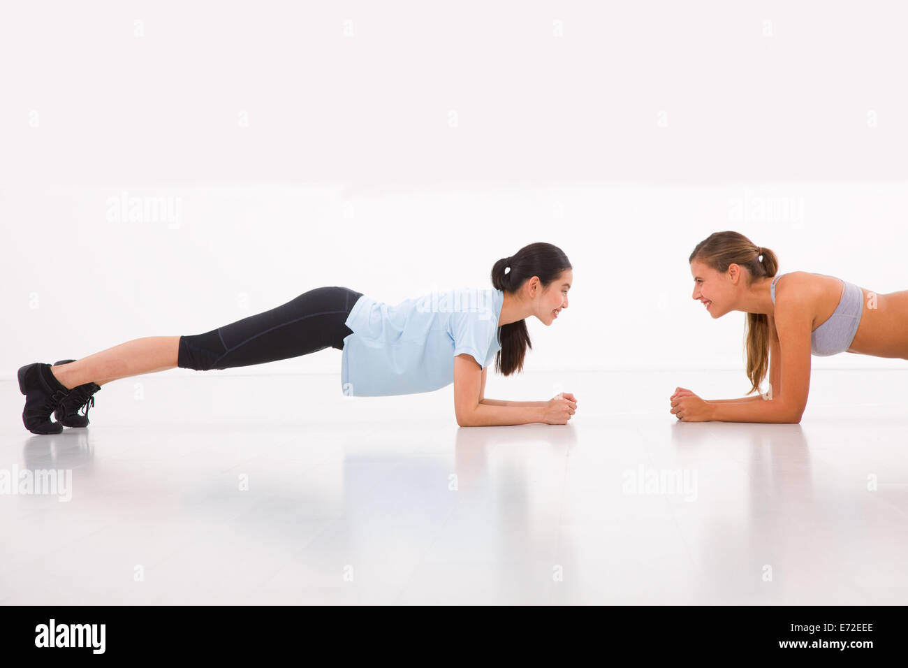 Two happy young woman doing push-ups in gym Stock Photo