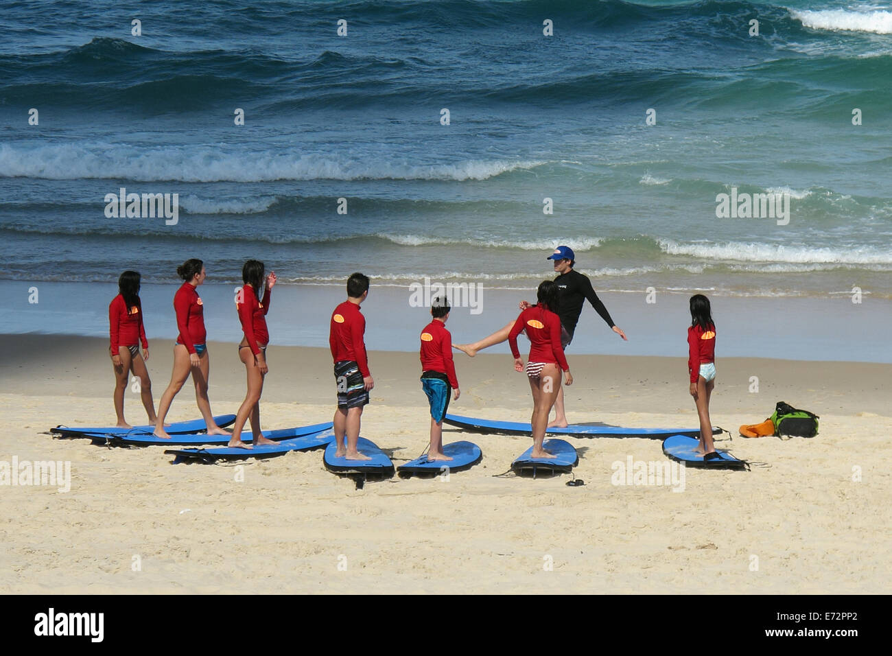 Teenagers having a lesson for surf board riding on Surfer's Paradise beach on the Gold Coast in Australia Stock Photo