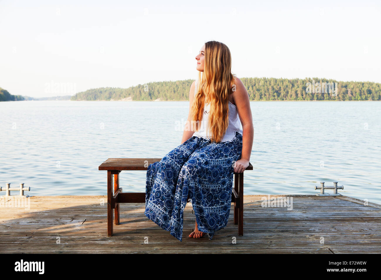 View of teenage girl (16-17) sitting beside river Stock Photo