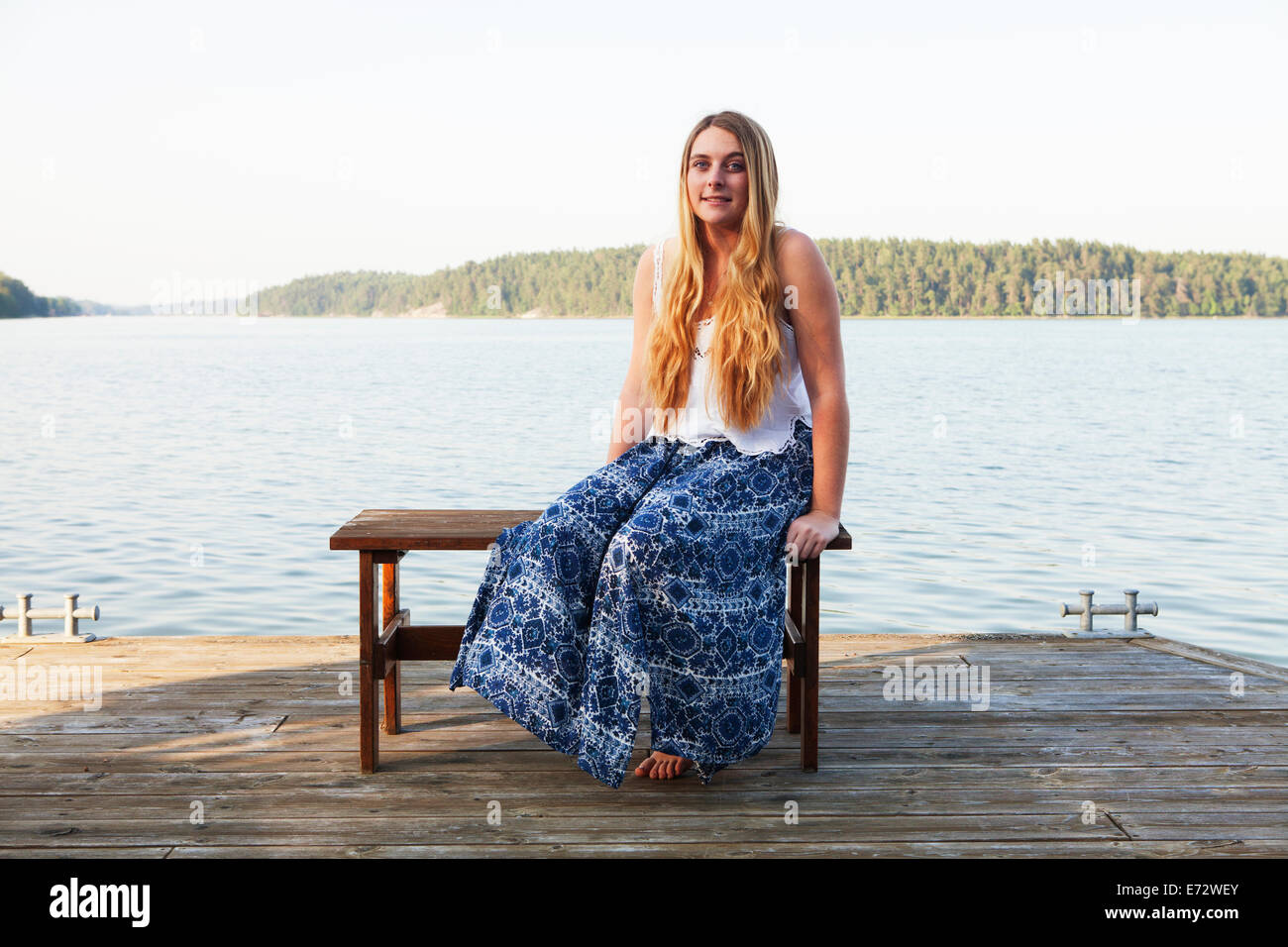 View of teenage girl (16-17) sitting beside river Stock Photo