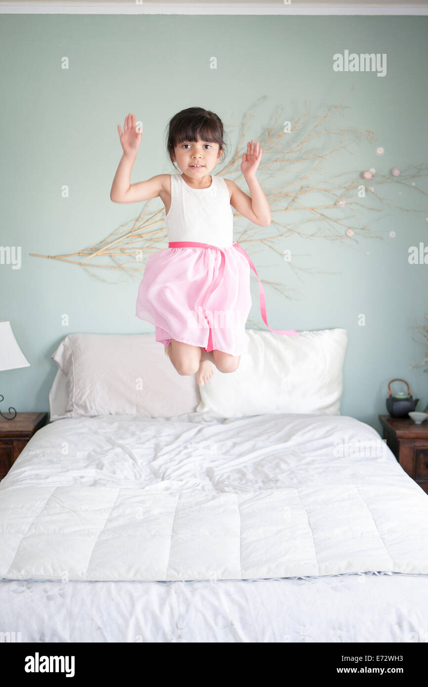 Girl (6-7) jumping on bed Stock Photo