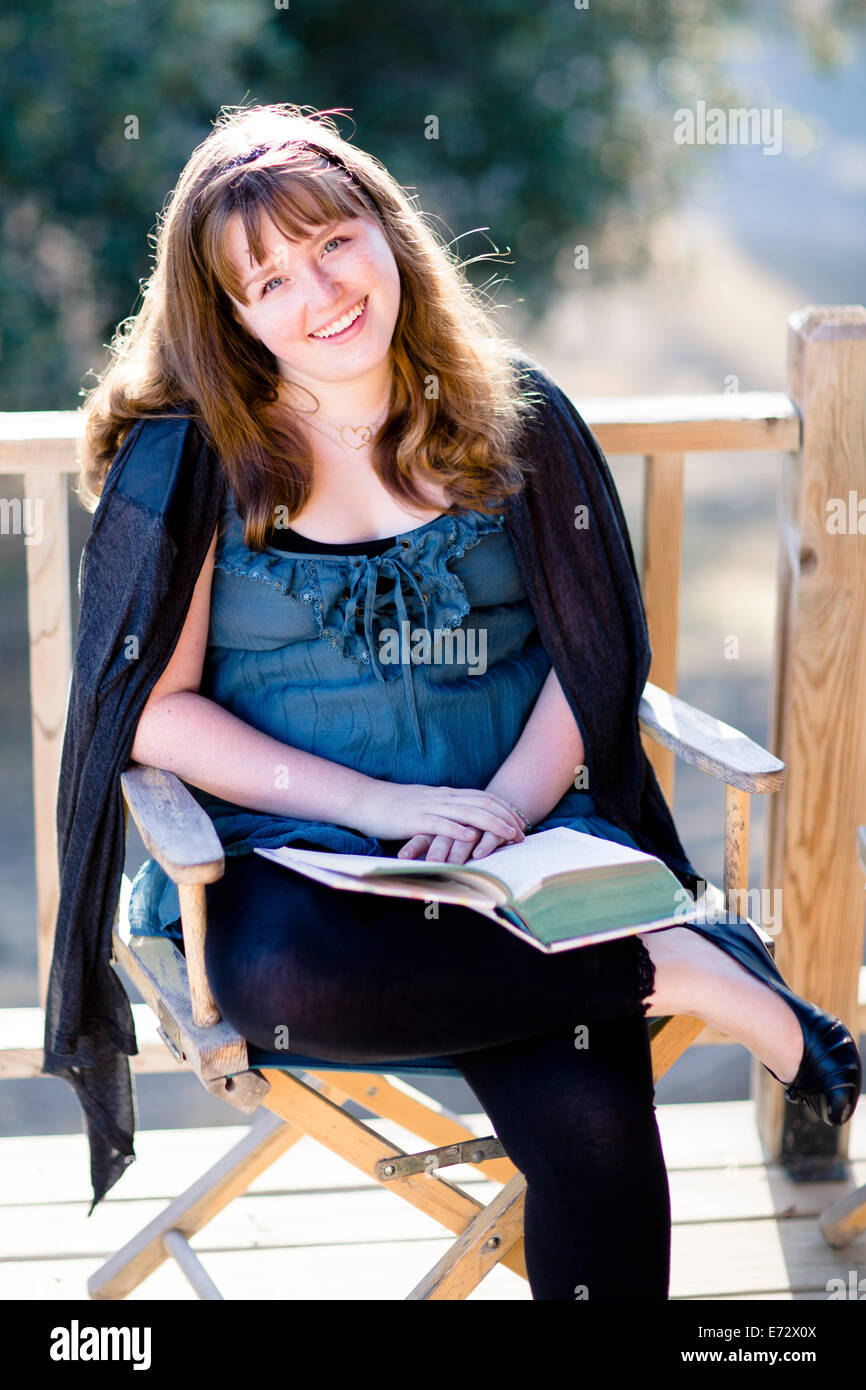 Portrait of teenage girl (13-15) with book on porch Stock Photo
