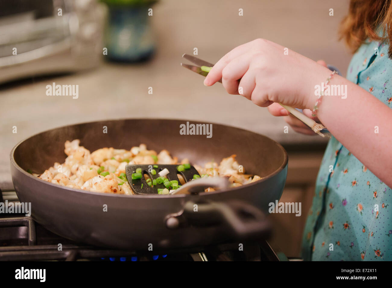 Teenage girl (13-15) cooking in kitchen Stock Photo