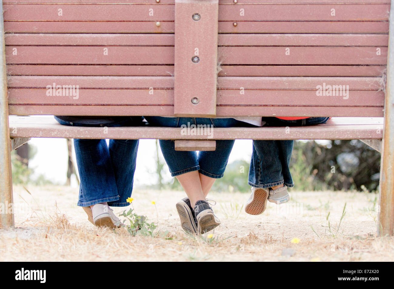 Female girlfriends (6-7, 10-12, 13-15) sitting on bench Stock Photo