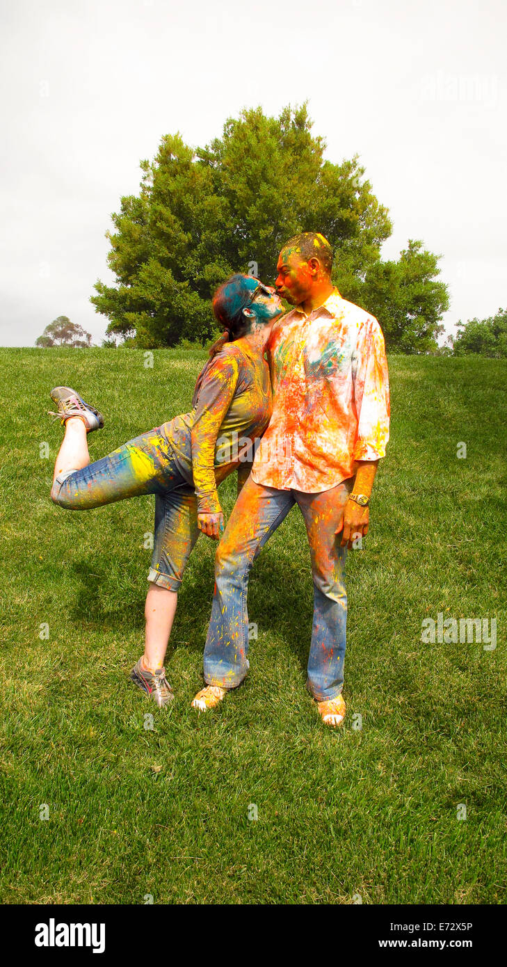 Couple covered in colorful paint kissing Stock Photo