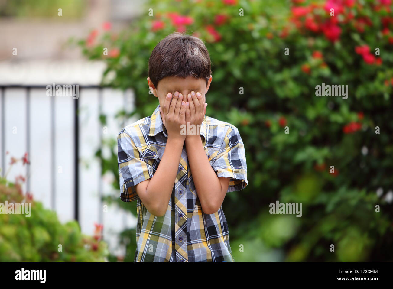 Young boy covers his eyes with hands Stock Photo