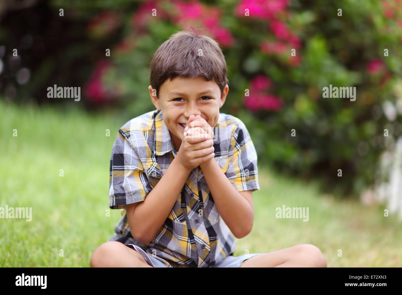 Young boy sitting outside laughing Stock Photo