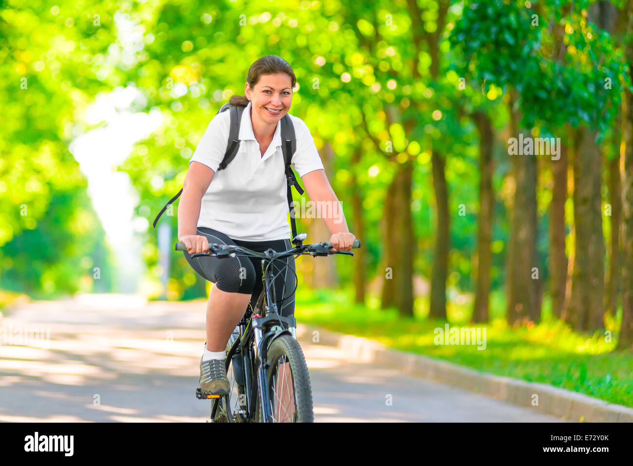 Joyful girl on a bicycle with a backpack Stock Photo