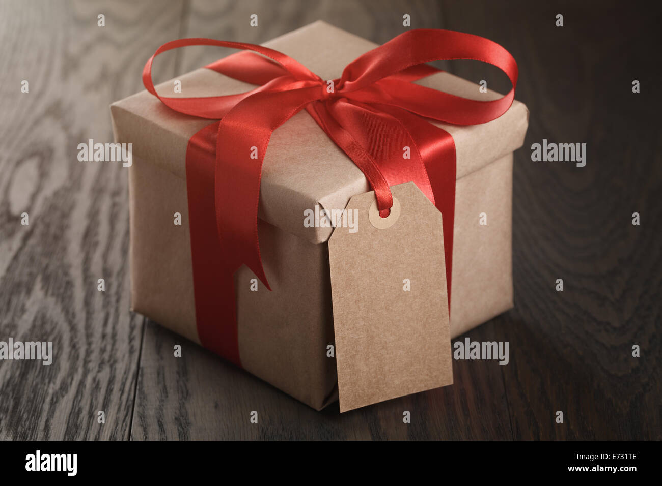 rustic gift box with red ribbon bow and empty tag, on old wood table ...
