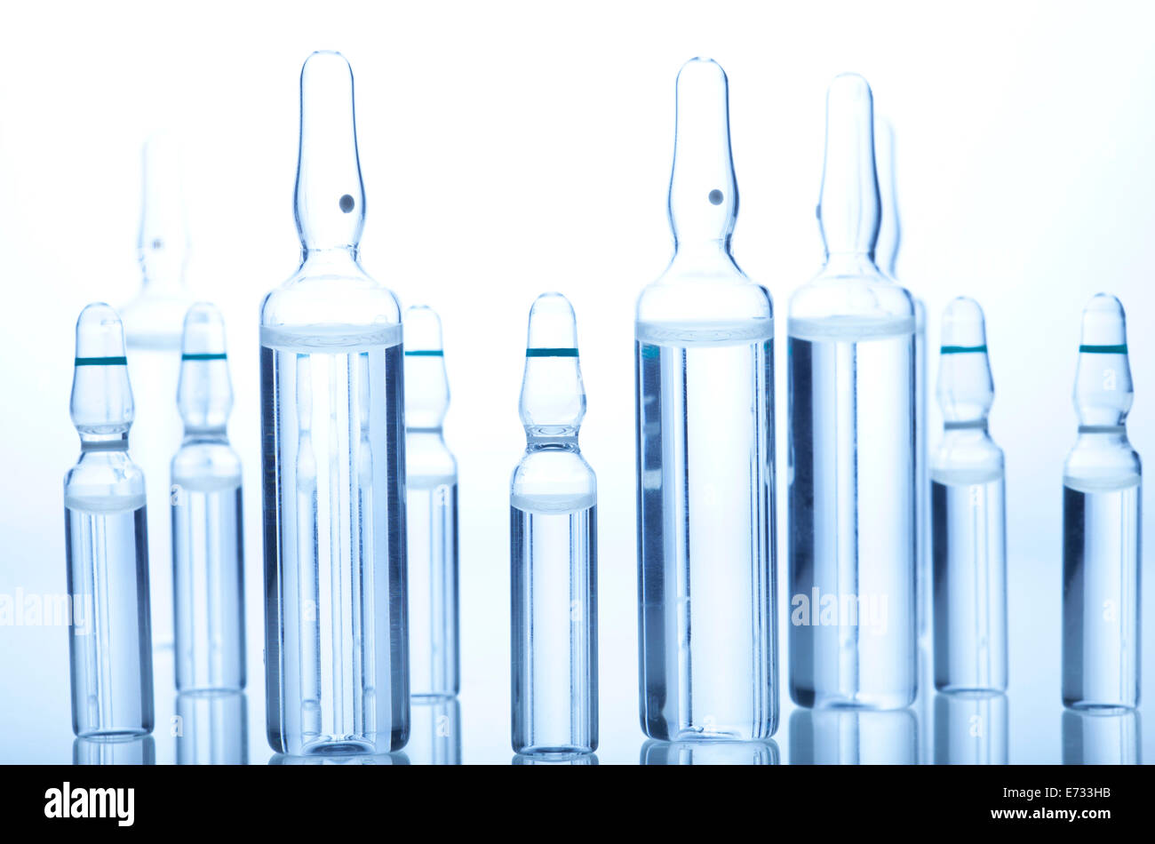 Glass Medicine Ampoules with liquid on a white and blue background Stock Photo