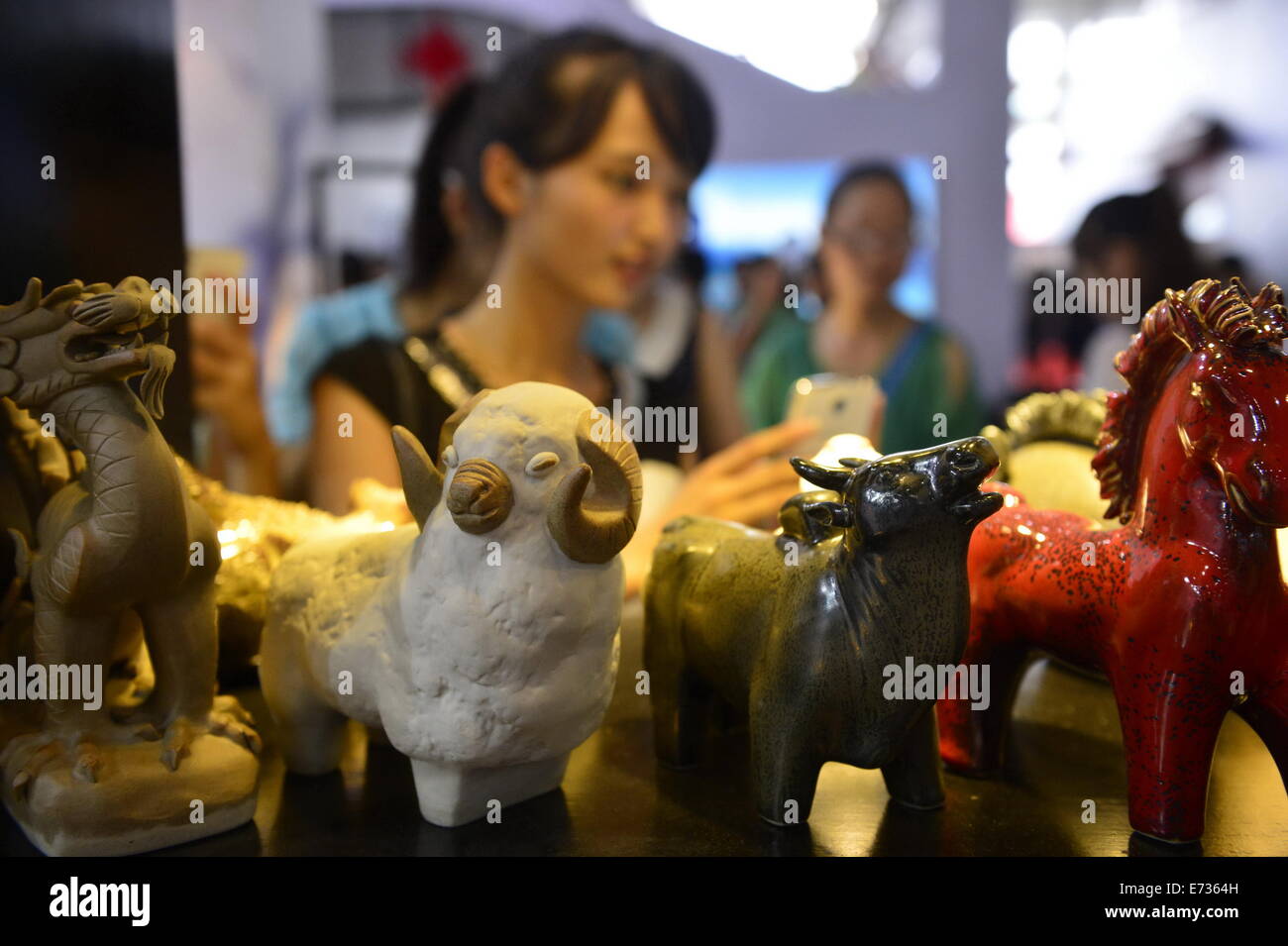 Nanchang, China's Jiangxi Province. 5th Sep, 2014. A visitor takes photo of sculptures from Jingde Town during the Jiangxi Tourism Product Fair in Nanchang, capital of east China's Jiangxi Province, Sept. 5, 2014. The three-day fair, which kicked off on Friday, presented more than 3,000 items of Chinese tourism commodities, including 38 intangible cultural heritage items in Jiangxi. © Zhou Mi/Xinhua/Alamy Live News Stock Photo