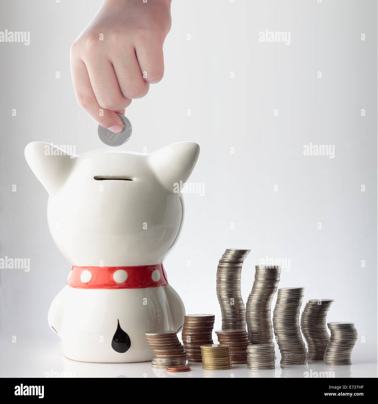 a hand saving coin in piggy bank on white background Stock Photo - Alamy