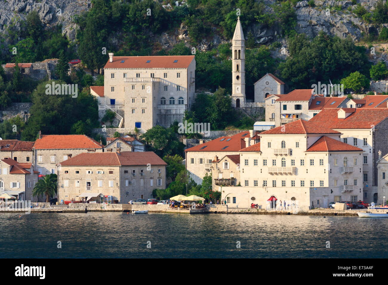 Church of Our Lady of the Rosary and a waterside restaurant lit by evening light, Perast, Bay of Kotor, UNESCO Site, Montenegro Stock Photo