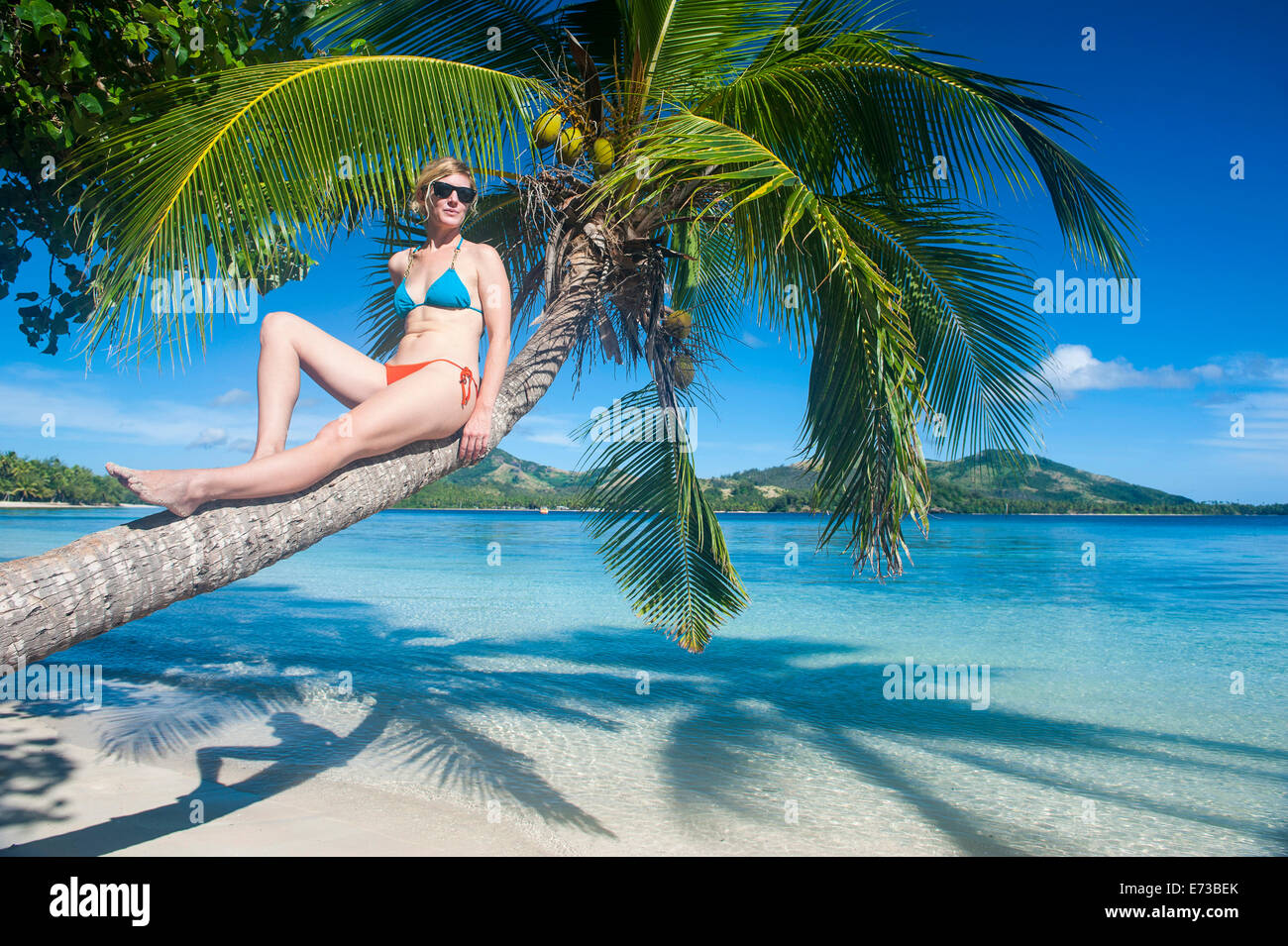 Woman relaxing on a palm tree on Nanuya Lailai island, the blue lagoon, Yasawas, Fiji, South Pacific, Pacific Stock Photo