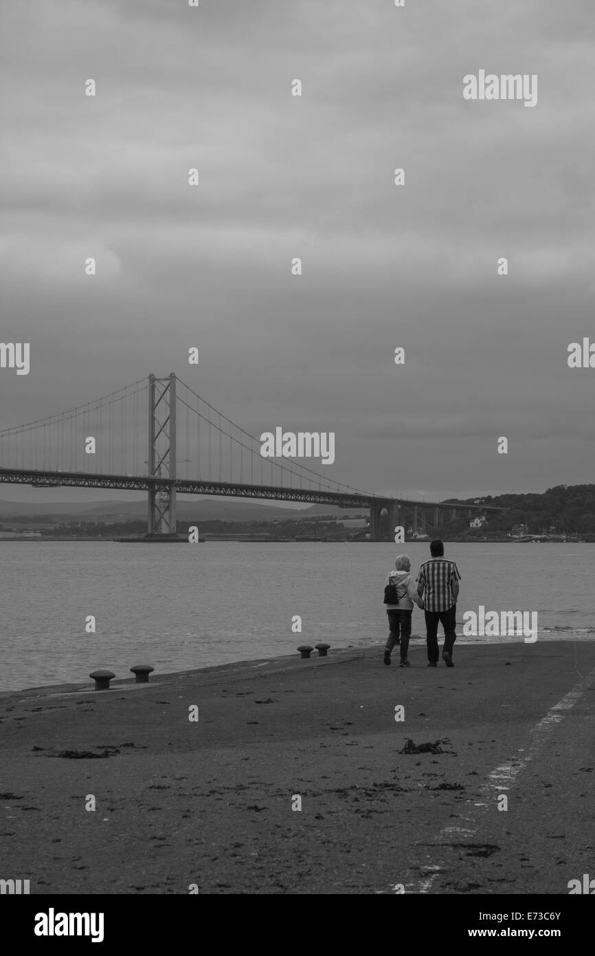Couple walking on pier at Forth Road Bridge Stock Photo