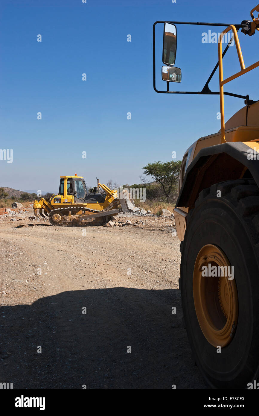 From side of haul truck to excavator working on construction of access road to new platinum mine. Dump truck waits to tip rock load.  South Africa Stock Photo