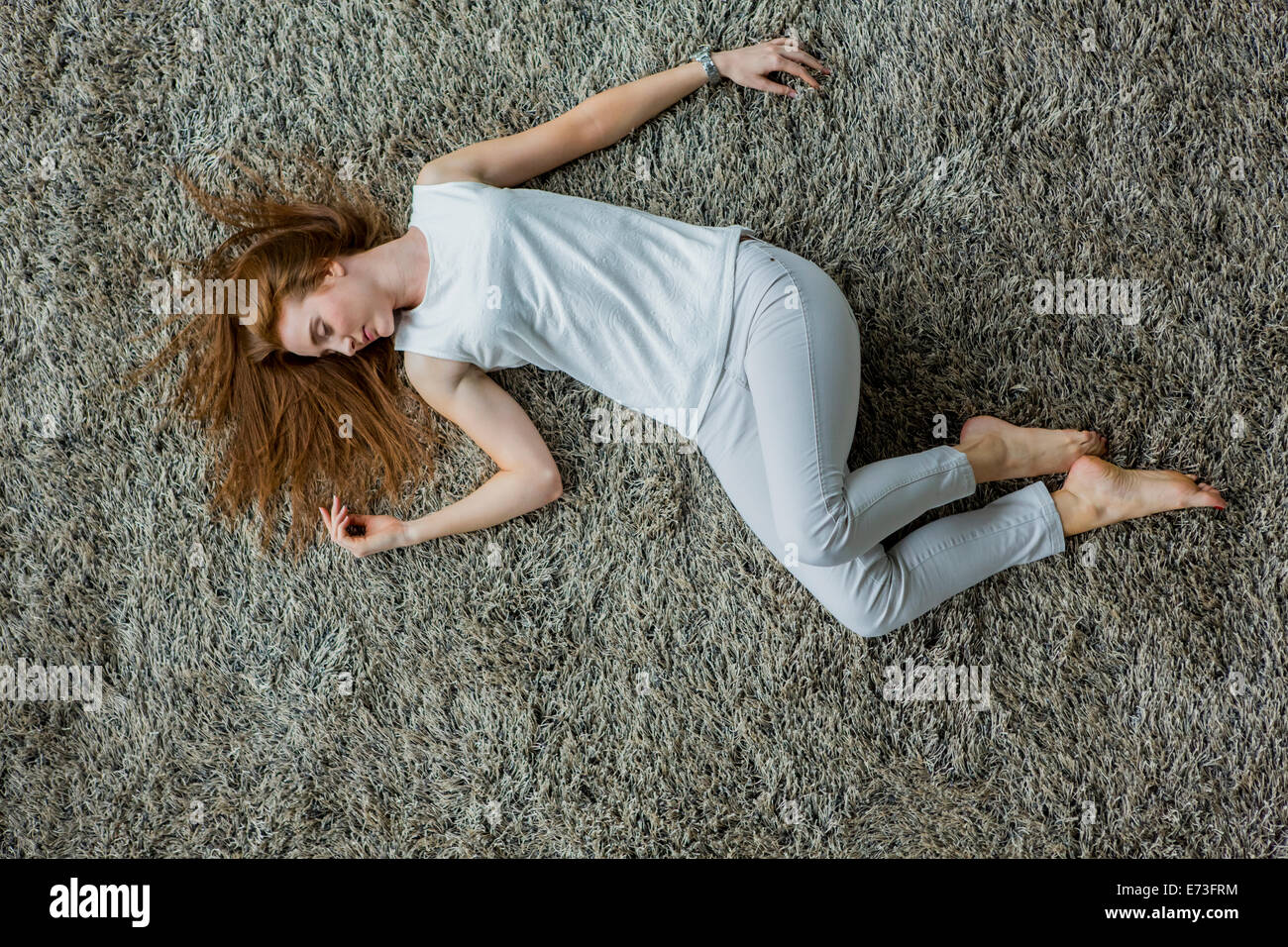 Young woman laying on the carpet Stock Photo - Alamy
