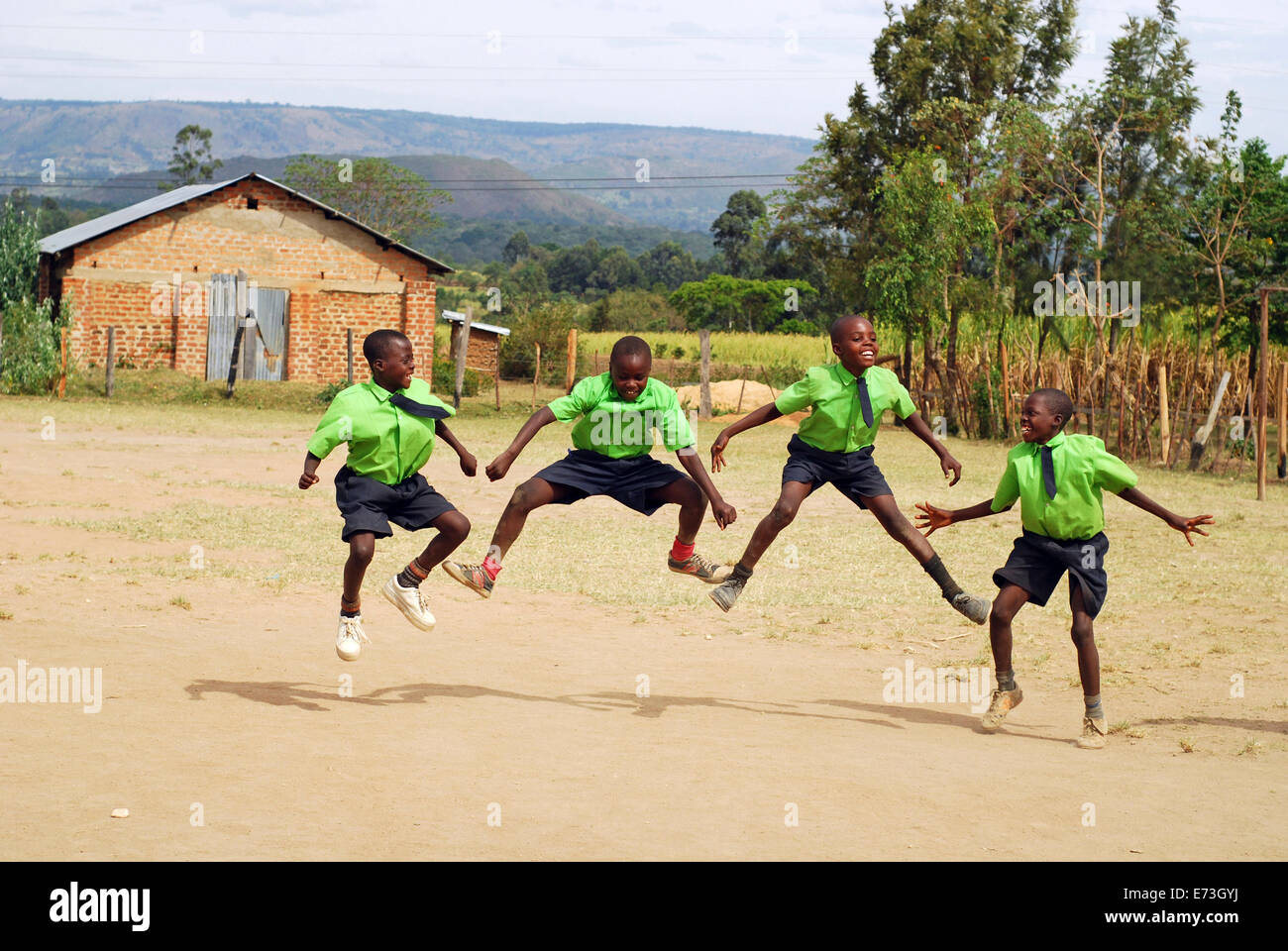 Kenya, Kakamega, 4 schoolboys jumping mid air in schoolyard (MR). Stock Photo