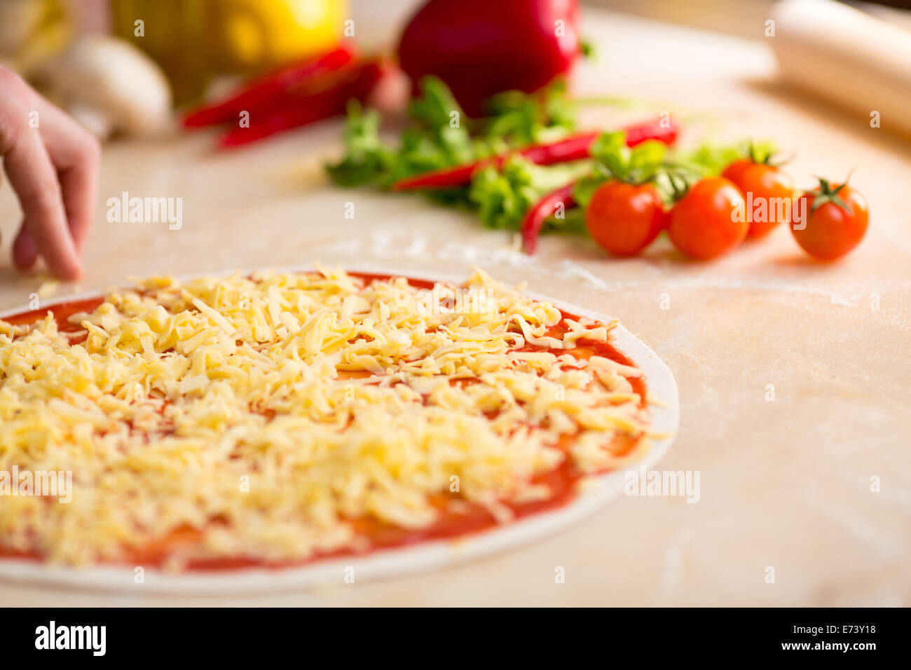 Italian pizza preparation. Cheese covering. Stock Photo