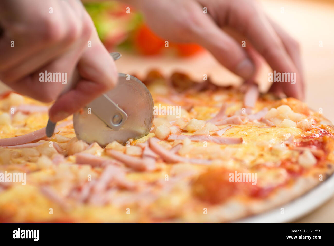 Pizza carbonara portions cutting by round knife Stock Photo