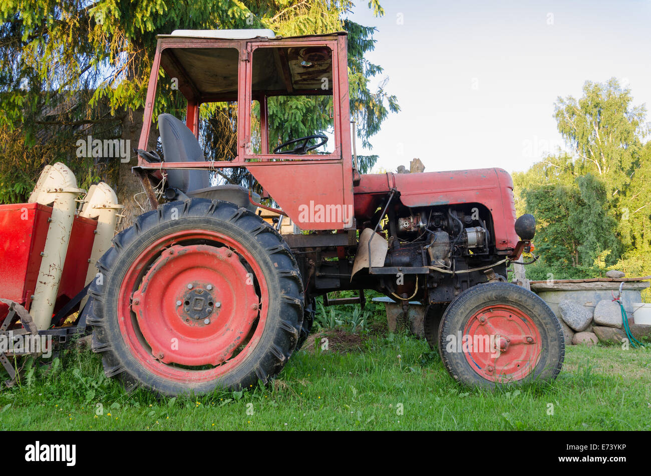 close up of old rural tractor with red wheels in garden nature Stock Photo