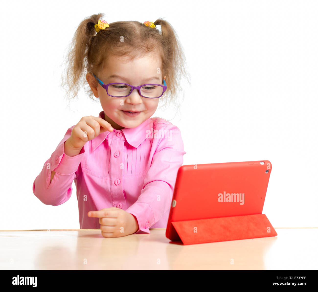 happy child in glasses looking at mini tablet pc screen sitting at table Stock Photo