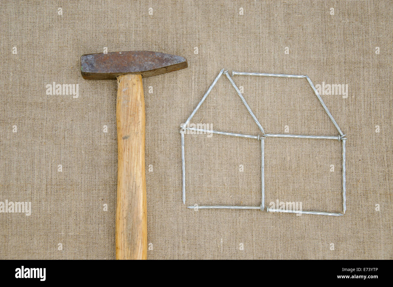 work hammer and outbuilding shape of metallic nail on linen texture background Stock Photo