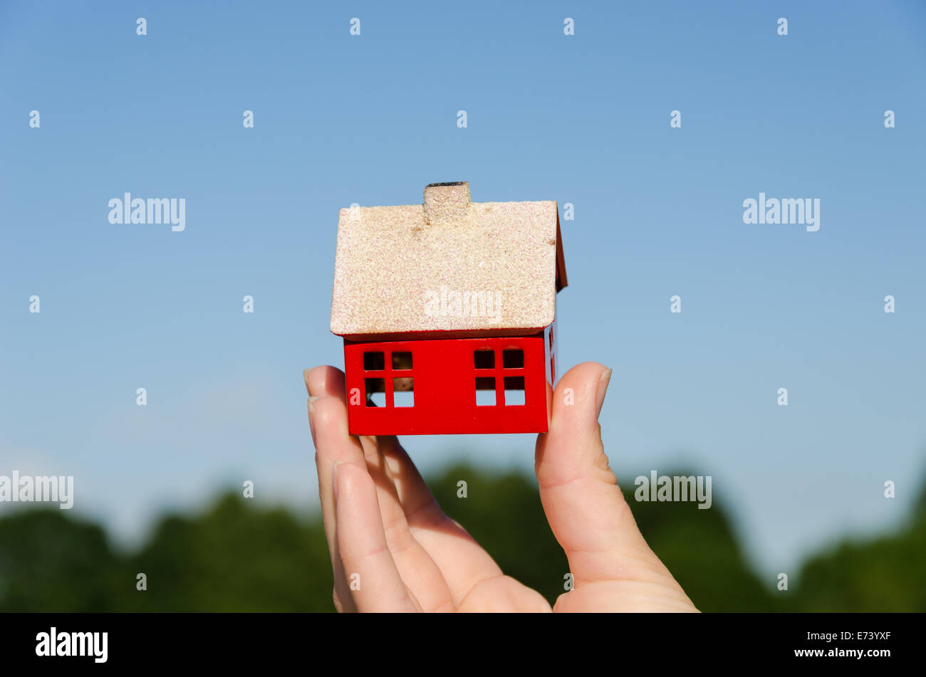 woman hand hold small metallic house miniature on blue sky background ...