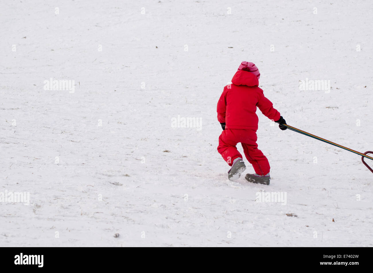 child with red waterproof overall in snow covered field in winter time Stock Photo