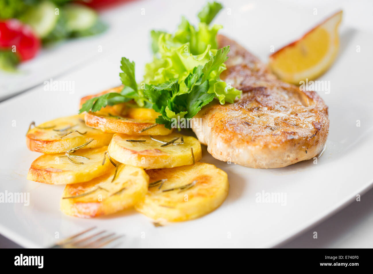 Roasted pork chop with potatoes on dish Stock Photo