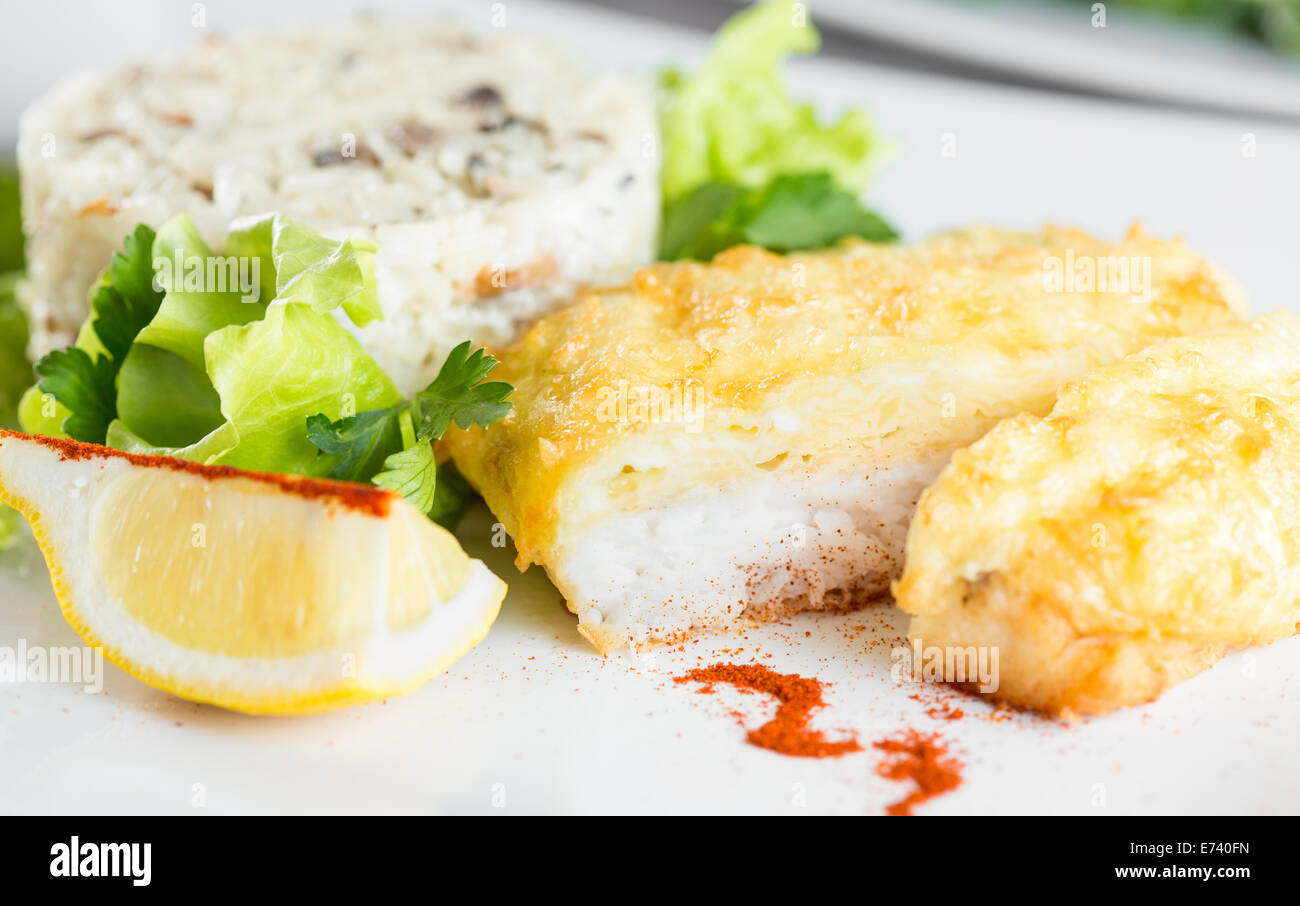 Fish fillet baked with cheese  and risotto with mushrooms Stock Photo