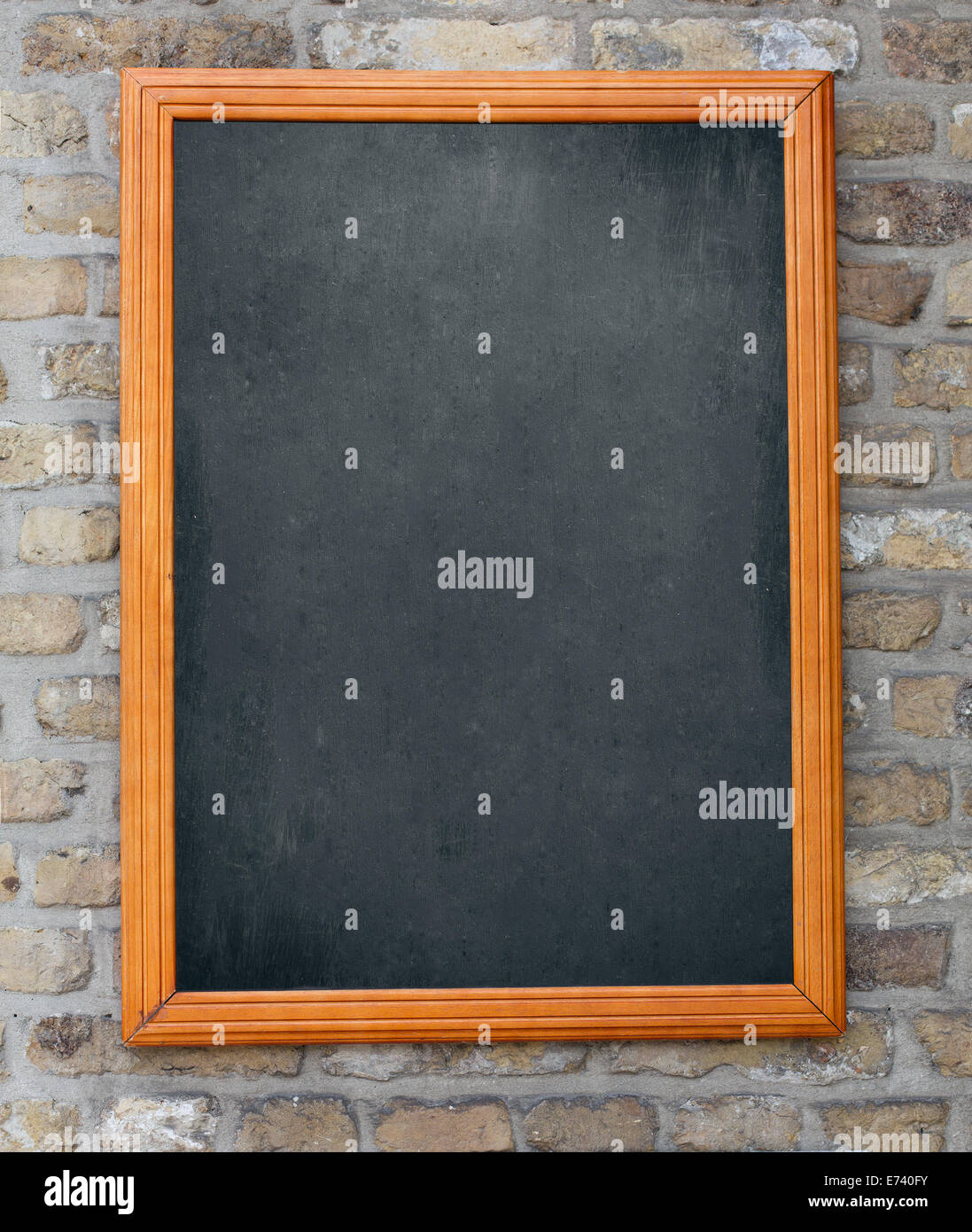 Aged blackboard hanging on brick wall as a background for your menu Stock Photo